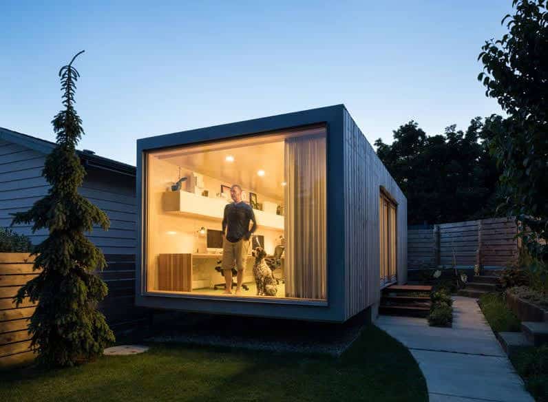 Man stood inside a converted container in a back garden.